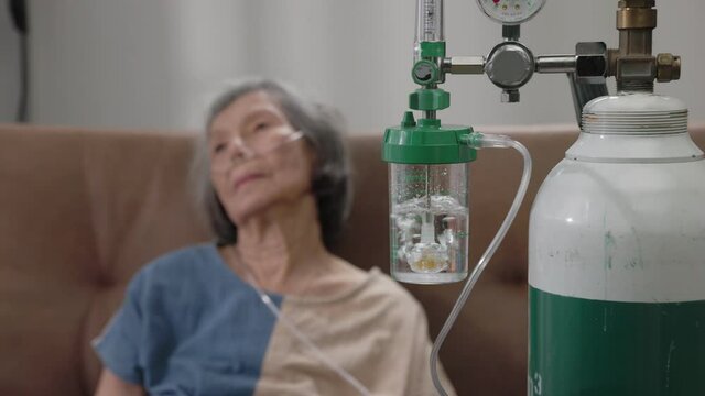 Elderly woman wearing oxygen nasal canula at home.