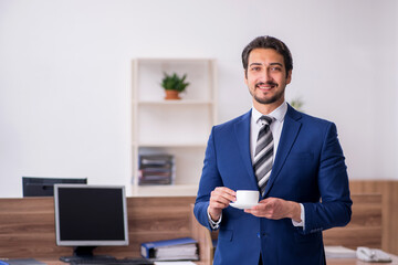 Young male employee drinking coffee during break