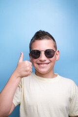 smiling boy on blue background. Hand shows ok sign