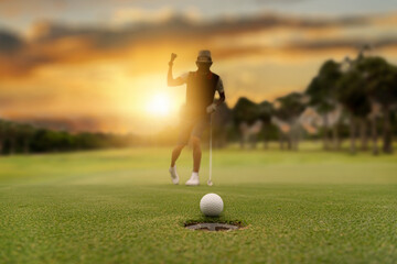 Silhouette golfer professional teeing golf ball to hole to winner in game at golf course with...