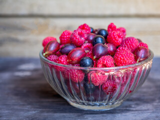 Summer berries in a glass vase close-up, on a rustic kitchen.