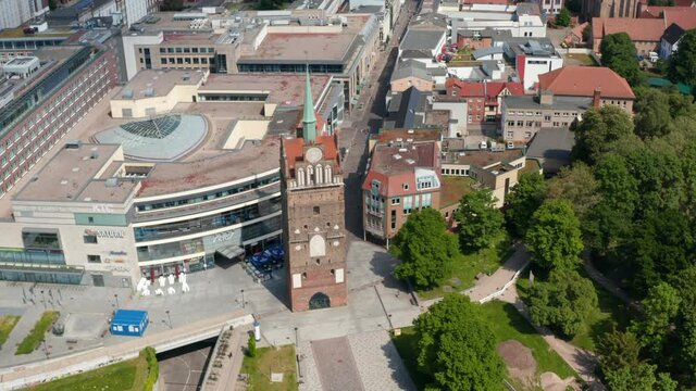 Aerial view of historic town gate Kropeliner Tor next to modern building of shopping centre. Tilt up reveal of city centre