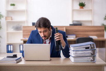 Young alcohol addicted male employee working in the office