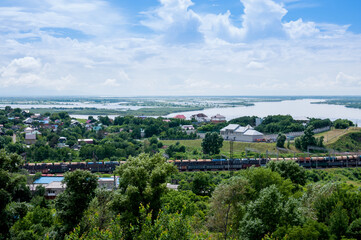 Summer Russian landscape, cottages on the banks of the Amur River and a passing train