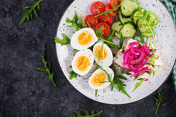 Breakfast. Boiled eggs salad with greens, cucumbers, tomato and sandwich with ricotta cheese, fried chicken fillet and red onion. Keto/paleo lunch. Top view, overhead