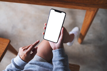 Top view mockup image of a woman holding mobile phone with blank white desktop screen
