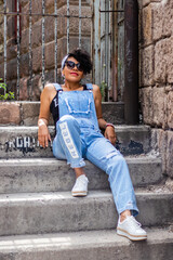 Mid adult afro mexican smiling woman sitting on some urban steps relaxing