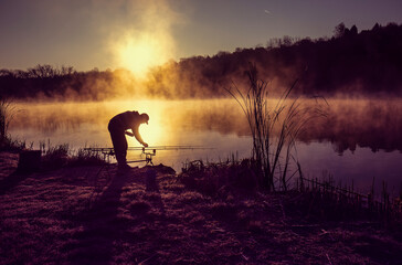 Silhouette of fisherman at lakeside in morning hours