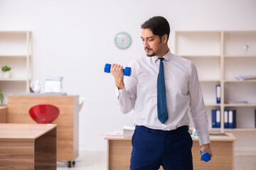 Young male employee doing sport exercises during break