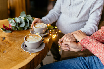 Pure love concept. Close up of male and female holding hands, pregnant future mother. Young couple spending time in indoor cafe.