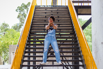 Fototapeta na wymiar Mid adult afro mexican woman posing on some urban steps with yellow hand rails
