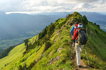 Fototapeta na wymiar Wandergruppe begeht einen grasigen Grat im Gebirge
