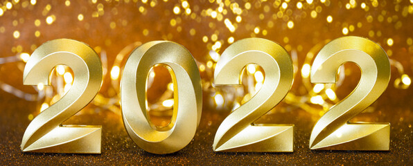 On a defocus background with light bulbs are the golden numbers of the new year 2022