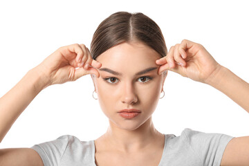 Beautiful young woman doing facial yoga on white background
