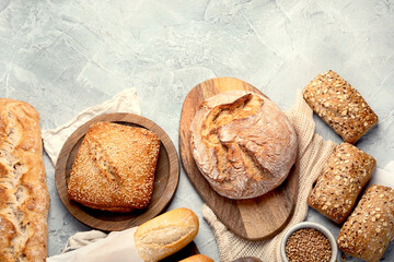 Various types of fresh baked bread on light gray background.