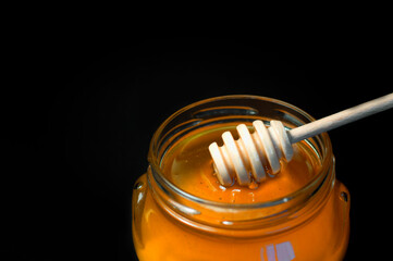 fresh honey is poured into a transparent jar on a black background. High quality photo