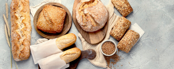 Various types of fresh baked bread on light gray background.