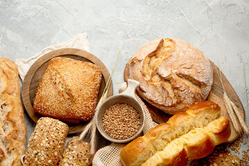 Various types of fresh baked bread on light gray background.
