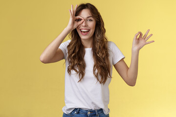 Friendly charismatic enthusiastic happy woman having perfect day show okay ok circle gesture look through ring amused wondered smiling broadly delighted express joy admiration yellow background - obrazy, fototapety, plakaty
