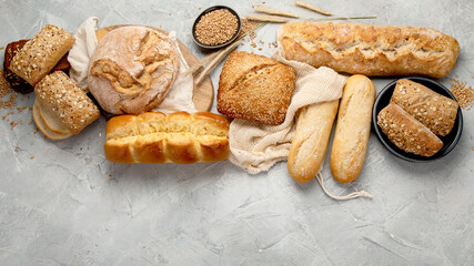 Various types of fresh baked bread on light gray background.