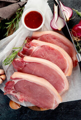 Sliced raw pork meat on dark gray background. Organic gourmet food concept.