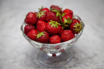 glass transparent bowl with strawberries on gray table