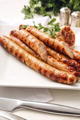 Plate with tasty grilled sausages on light background, closeup
