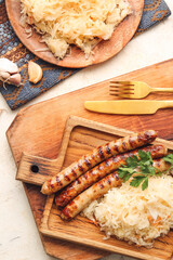 Board with tasty grilled sausages and sauerkraut on light background, closeup
