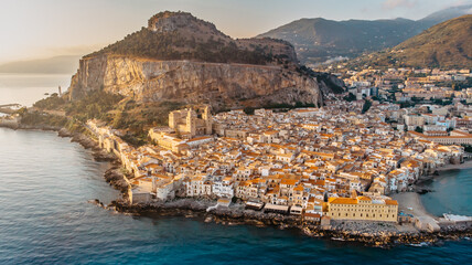 Sunrise over harbor in Cefalu, Sicily, Italy, panoramic aerial view of old town with colorful waterfront houses, sea and La Rocca cliff.Attractive summer cityscape,travel holiday concept background.