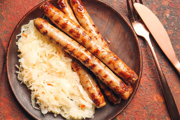 Plate with tasty sauerkraut and grilled sausages on grunge background, closeup