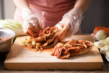 Woman making kimchi cabbage on wooden board, Popular homemade Korean traditional fermented side dish food - obrazy, fototapety, plakaty