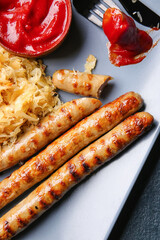 Plate with tasty sauerkraut, grilled sausages and sauce, closeup