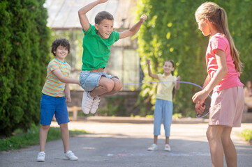 Obraz premium Jumping boy and friends with skipping rope