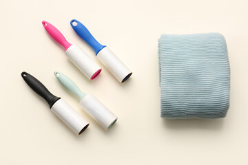 Lint rollers and clothes on color background