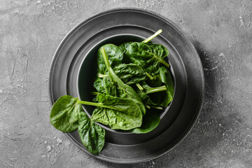 Bowl with fresh spinach leaves on grunge background