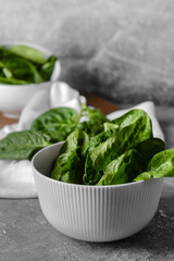 Bowl with fresh spinach leaves on grunge background, closeup