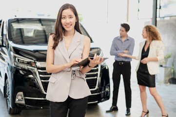 Portrait photo of young professional look Asian automobile sales agent standing in front of new car...