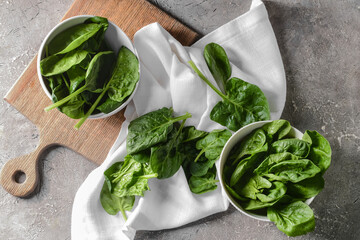 Bowls with fresh spinach leaves on grunge background