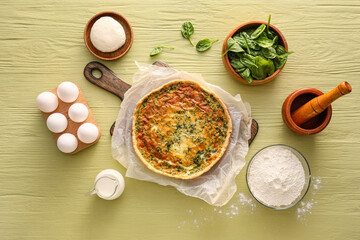 Spinach tart and ingredients on color wooden background