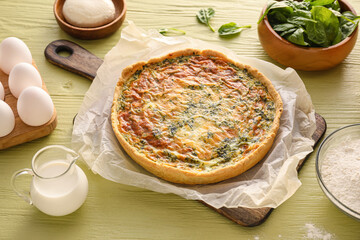 Spinach tart and ingredients on color wooden background