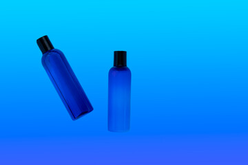 Cosmetic bottles with refreshing shampoo and lotion on a blue background, top view. Packaging for branded products.Blue on blue.
