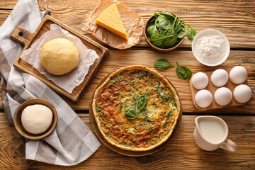 Spinach tart and ingredients on wooden background