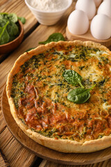 Spinach tart and ingredients on wooden background