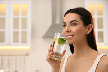Young woman with glass of fresh lemonade at home, space for text