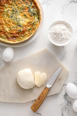 Spinach tart and ingredients on light background
