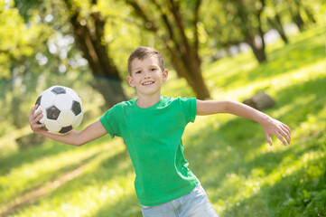 Joyful boy running with ball in park