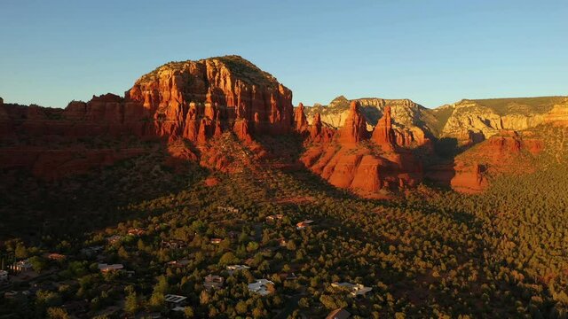 Majestic Red Sandstone Cliffs Towering On The Countryside Town Of Sedona During Sunset In Arizona, USA. - Aerial Shot