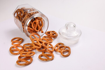 Pretzel cracker in a glass jar pouring dropping on white background