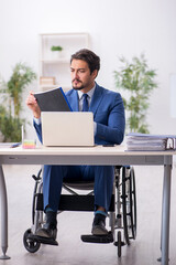 Young male employee in wheel-chair at workplace