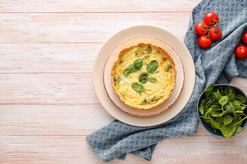 Tasty spinach tart and tomatoes on light wooden background
